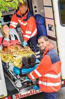 Paramedics helping woman on stretcher in ambulance