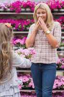Child presenting flowers to her mother in garden center