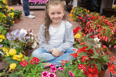 Little girl sitting on path surrounded by flowers