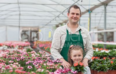 Little girl and gardener standing in greenhouse