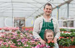 Little girl and gardener standing in greenhouse