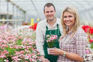 Smiling woman holding flower pot with employee