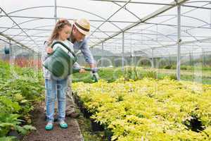 Gardener helping little girl watering plants