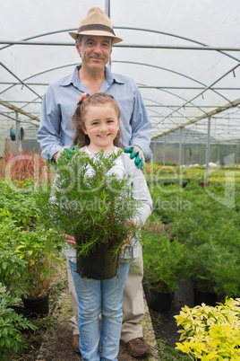 Little girl holding potted plant with grandfather