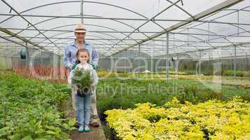 Gardener and granddaughter holding a large potted plant