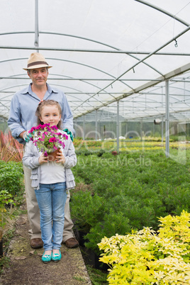 Little girl holding flower pot standing with her granddad