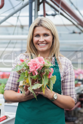 Blonde woman holding a flower working in garden center