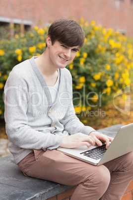 Man sitting at the wall holding a laptop