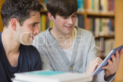 Man holding a tablet PC at the library smiling