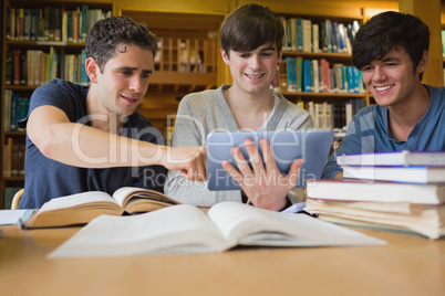 Young man pointing something out on tablet pc with others