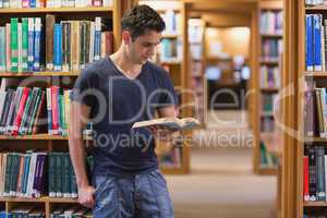 Man standing at the library holding a book