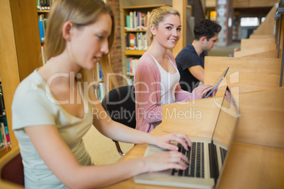 Woman using tablet pc looking up from studying