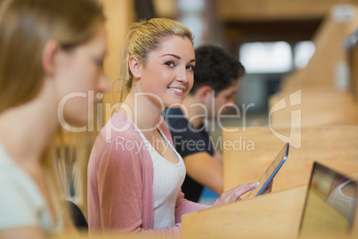 Student with tablet pc looking up from studying