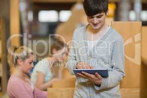 Man standing in library holding a tablet computer