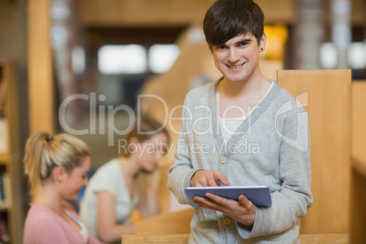 Man holding a tablet pc while standing at the library Man holding a tablet pc while standing at the library