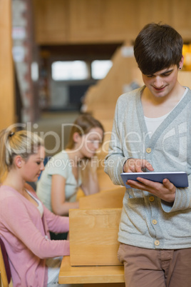 Man standing in the library holding a tablet pc while smiling Man standing in the library holding a tablet pc while smiling