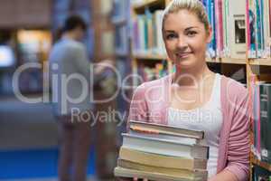 Woman holding pile of books in college library