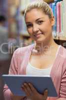 Woman standing at the library holding a tablet computer