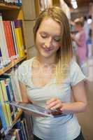 Woman standing at a bookshelf with tablet pc