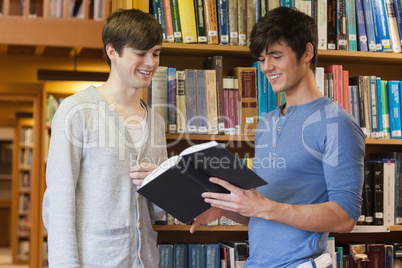 Students standing in library looking at book