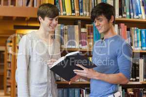 Students standing in library looking at book