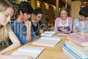 Students studying together in library with one using a tablet pc