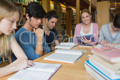 Woman holding a tablet pc sitting at table in library