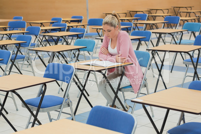 Student studying at desk in empty exam hall