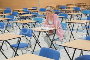 Student studying at desk in empty exam hall