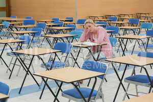 Student studying in empty exam hall