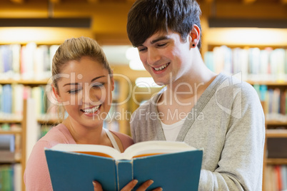 Couple standing holding a book in the library