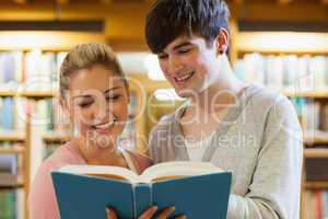 Couple standing holding a book in the library