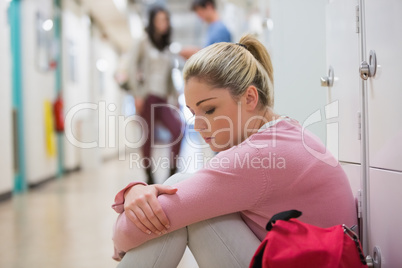Student sitting on the floor at the hallway looking disappointed