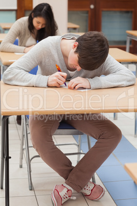 Student writing at desk