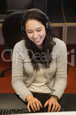 Female student sitting at the computer with headphones