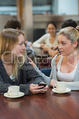 Student comforting upset friend with mobile phone