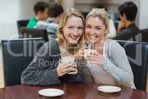 Women sitting at the coffee shop holding cups