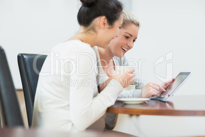 Smiling woman sitting while holding a tablet pc