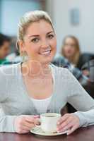 Woman sitting holding a cup of coffee in college cafe