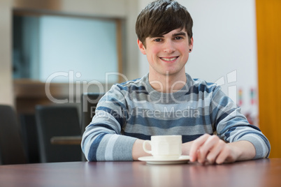 Student sitting at table drinking coffee in college cafe