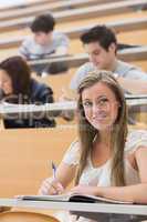 Woman sitting while smiling and taking notes