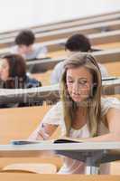 Woman sitting in lecture while writing notes