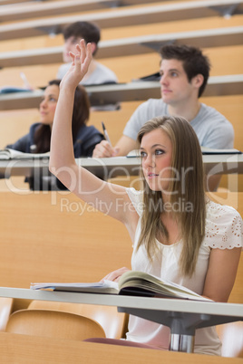 Woman sitting at the lecture hall with hand up