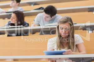 Student sitting at the lecture hall holding a tablet pc