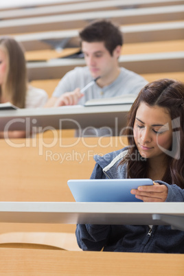 Woman sitting at the lecture hall holding a tablet computer