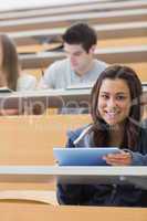 Woman holding a tablet pc while smiling in lecture hall