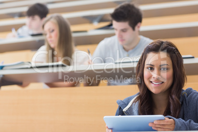 Smiling student taking notes with tablet pc