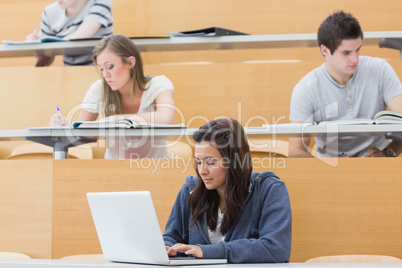 Students in a lecture with one using laptop