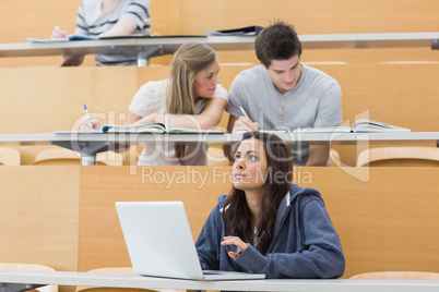 Students sitting in lecture with girl thinking at laptop