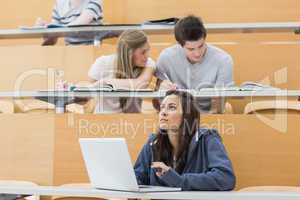 Students sitting in lecture with girl thinking at laptop